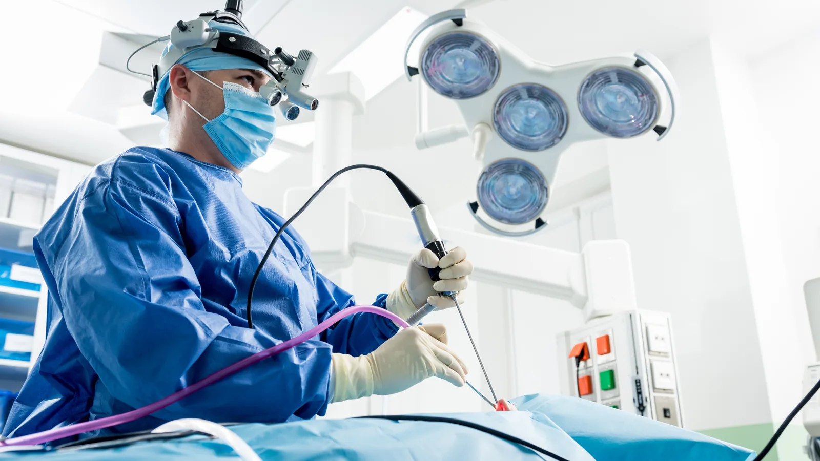 Cirurgião com lupa cirúrgica e endoscópio em centro cirúrgico, durante cirurgia endoscópica nasal.
